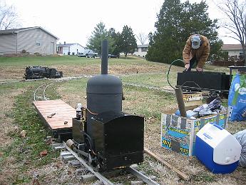  Saturday, 29-Nov-08, a steamup at Tim M.'s private track at his house. The crab is unloaded and a borrowed flatcar is the engineers seat.  To the right John T. fills the tender of his freshly shopped Atlantic, Tim's consolidation awaits its master in the background.